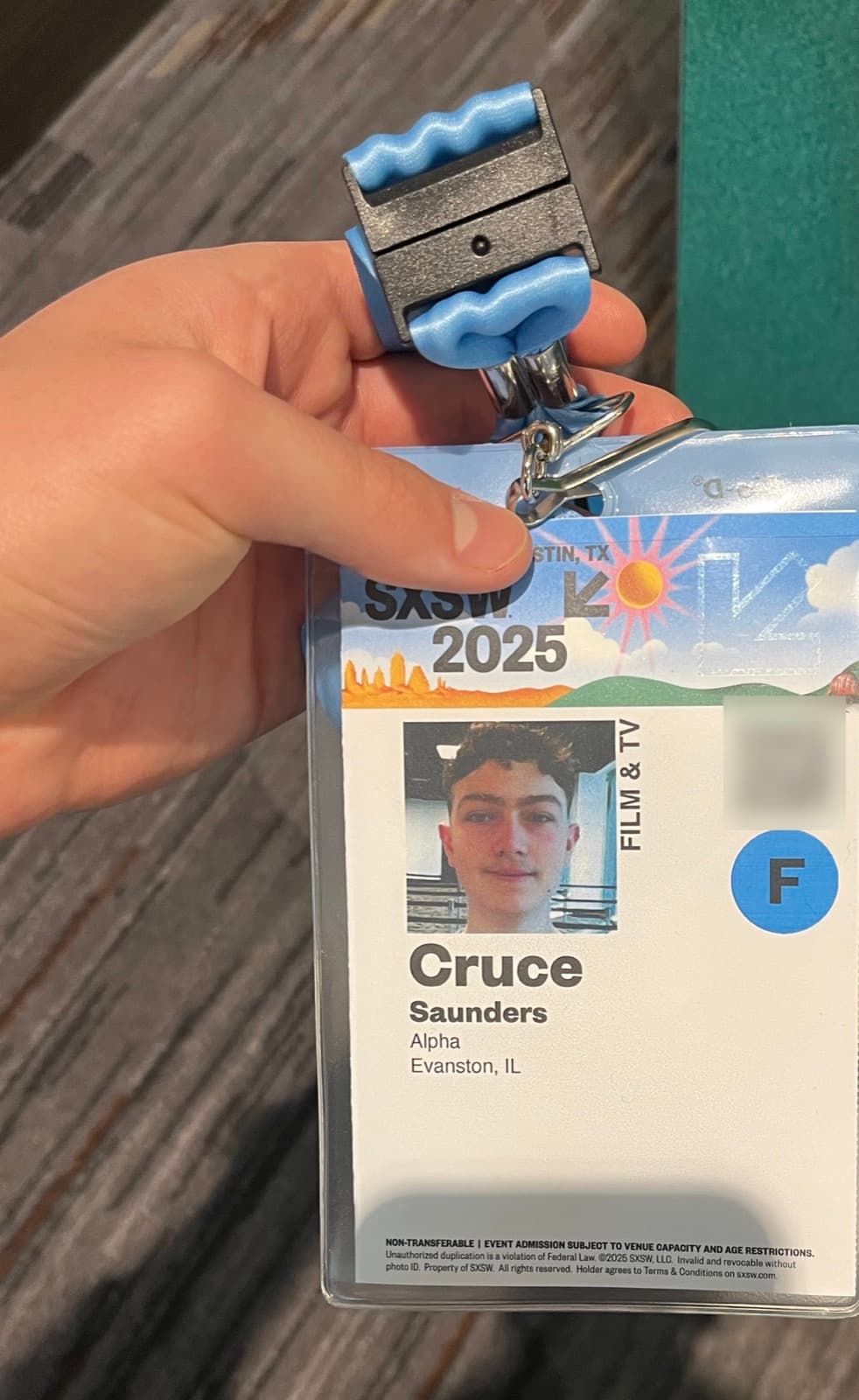 Cruce holding up his SXSW 2025 Film & TV badge on its lanyard.